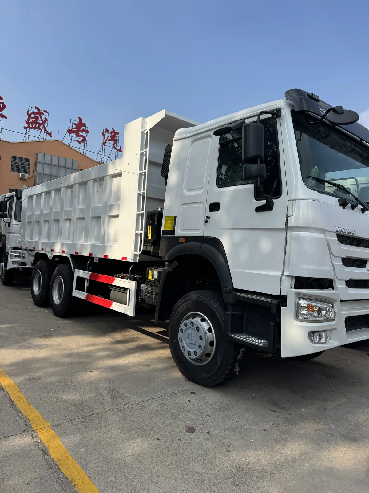 Front and side view of a white HOWO dump truck